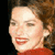 Static 50x50 pixel icon showing a close-up of a person's face with brown hair, red lips, and a red garment against dark background.