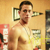 A shirtless man with short dark hair and a beaded necklace stands against a yellow wall with black-and-white pennants and red posters, with 'not' text overlaid in yellow and red.