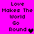 Pixelated text "Love Makes The World Go Round" on bright pink background with two heart symbols, one black and one purple.