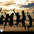 Silhouettes of multiple figures jumping against a sunset sky with clouds, each figure in mid-air pose.