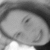 Black-and-white image of a person with dark hair smiling, showing teeth, in a with four