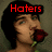 A pixelated image of a person with dark hair holding a red rose, with red text above the head reading 'Haters', 'Make Me', and 'Famous' across three