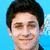 Pixelated portrait of a person with short dark hair against solid light blue background, smiling expression visible in facial features.