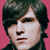 Static pixelated image of a person with dark hair against a solid pink background, showing partial facial features including eyes, nose, and mouth.