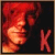 Pixelated static icon showing a red-haired figure in profile with a large stylized 'K' on the right side against dark background.