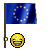Blue flag with yellow circle of stars on pole, below a smiling emoji face.