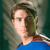 Pixelated close-up of a person with brown hair wearing a blue top against a blurred greenish background.