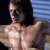 Pixelated image of a shirtless person with dark hair, facing left against a striped background.