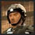 Pixelated image of a person wearing a white helmet and dark uniform with visible straps, set against a blurred brown background.