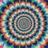 A circular, multicolored, pixelated spiral pattern with text elements arranged around it.