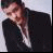 A man in a black suit with an open collar appears in three sequential poses against a light background, showing slight movement from left to right.