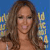 A pixelated close-up of a person with long brown hair against a blue background with blurred colorful shapes.