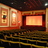 Pixelated image of a theater interior with warm orange and brown tones, featuring a stage area and decorative architectural elements.