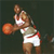 Pixelated static image of a basketball player in mid-action holding an orange ball, wearing white and red athletic uniform against dark background.