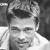 Black-and-white pixelated static image of a person's face with visible hair and shoulder, rendered in low-resolution grayscale with dithering effects.