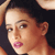 Pixelated close-up of a person's face with light brown hair, pink lips, and dark eyes against a black background.