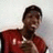A person in a red sleeveless shirt with white accents holds a brown object against a light background, showing slight head and hand movement across frames.