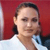 A pixelated close-up of a person with light skin tone wearing a white shirt against a solid red background.