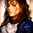 Pixelated static image of a person with long brown hair wearing a white top and dark blue garment, rendered in low-resolution 256x256 pixels.