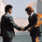 Animated contact sheet showing three sequential frames of two men in business suits shaking hands with one man's head on fire against a cityscape background.