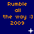 Blue background with orange text reading "Rumble all the way :) 2009" repeated in a , white star-like shapes scattered across the image