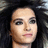 Pixelated close-up of a person's face with dark hair, neutral expression, and light skin tone against a dark background.