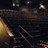 Pixelated dark scene with scattered light patches and faint diagonal lines on a black background.
