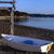 Static pixelated image of a small boat on calm water with a rocky shoreline and blue sky background.