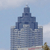 Static pixelated image of a tall blue-gray building with a stepped tower against a light blue sky background.
