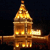 A pixelated golden structure resembling a tower with a spire, featuring multiple illuminated sections against a dark background.