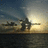 Pixelated landscape showing a body of water under a sky with a bright light source near the horizon, possibly a sunset or sunrise.