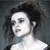 Pixelated grayscale portrait of a person with dark curly hair, light skin, and a white top against a dark background.