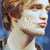 Pixelated profile portrait of a person with light brown hair and fair skin, shown in three with slight head movement against a blue background