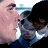 Pixelated image of two figures in close proximity, one with light skin and dark hair, the other with dark hair and a dark top, against a light background.