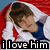 A person in a white jacket and blue shirt lies under red fabric with hands behind head, eyes closed, mouth slightly open; text "i love him" appears below.