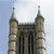 Pixelated static image of a building with two tall spires against a light blue sky background.