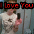A person in a white shirt holds a black phone, with red text reading "I Love You" above them against a light blue background.