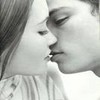 Black-and-white close-up of two people in profile facing each other with lips touching in a kiss, one with long hair and the other with short hair.