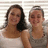 Two people stand side-by-side against a striped background, one in white sleeveless top and dark hair, the other in gray sleeveless top with light hair tied back.