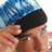 Pixelated close-up of a person wearing a blue patterned head covering and black cap, with visible skin tones and partial facial features.