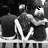 Three pixelated figures in grayscale, one holding a white object with black text on it.