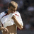 A person in a white shirt with red accents holds their chest, captured across three showing slight movement