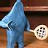 Pixelated static icon of a blue dolphin-like creature holding a white tennis racket against a brown background.