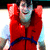 Pixelated static image of a person in a red martial arts uniform with a blue belt, arms raised in a celebratory pose against a blurred background.