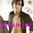 Pixelated image of a person with brown hair wearing an open dark jacket over a light shirt, standing against a white background with faint star-like shapes.