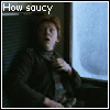 A person with red hair in a dark jacket adjusts their collar near a window, with text reading 'How saucy' in white on the left and red on the right.