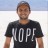 A pixelated image of a person wearing a black t-shirt with large white text, standing against a light background with a blue upper section.