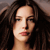 Pixelated close-up of a person with long dark hair, light skin, and closed eyes, rendered in warm brown and beige tones.