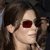 Pixelated close-up of a person with brown hair wearing dark red sunglasses, visible ear, and light skin tone.