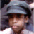 A pixelated close-up of a person wearing a light blue cap and white shirt, with dark hair visible beneath the cap.